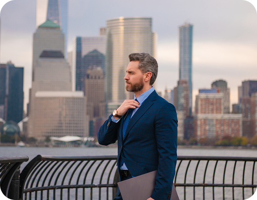 Business professional standing outdoors with a city skyline behind him